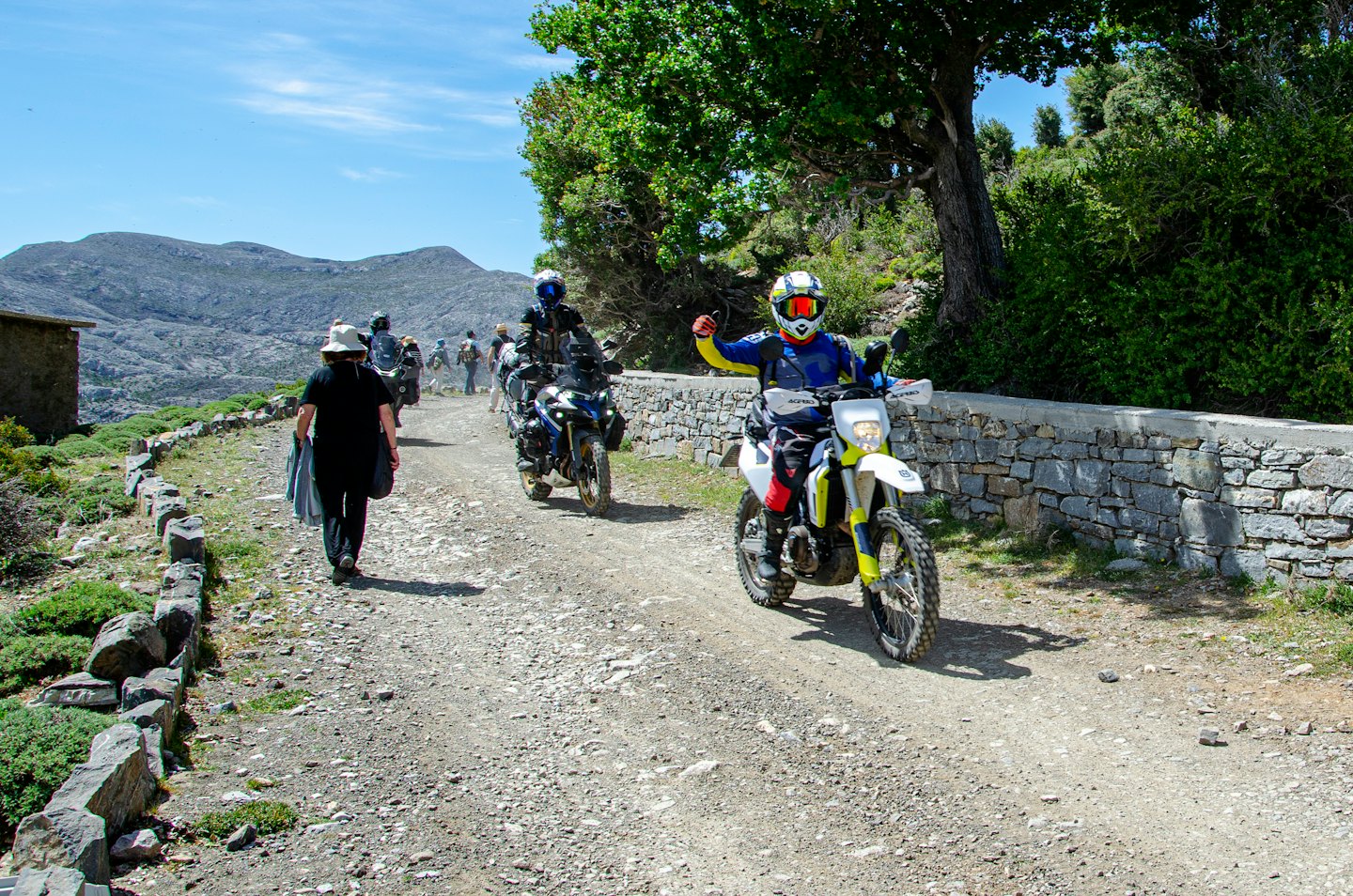 Motociclisti percorrono una strada sterrata in un paesaggio montano.